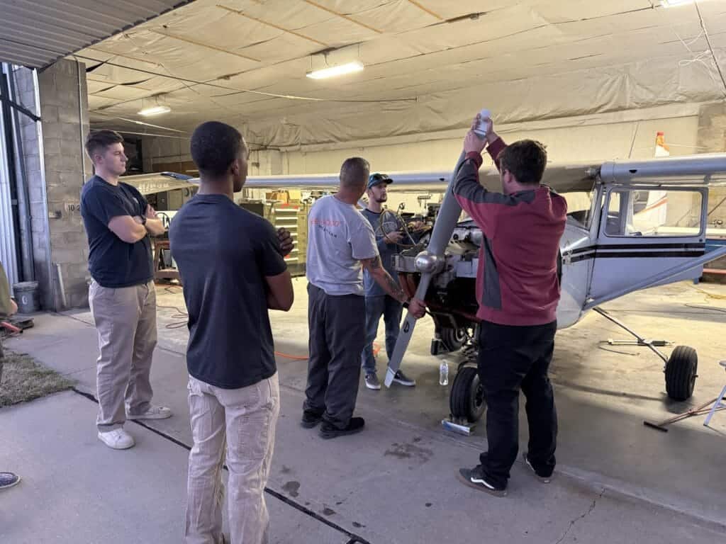 Aircraft maintenance in Kansas training session with students and instructor working on a small propeller plan.